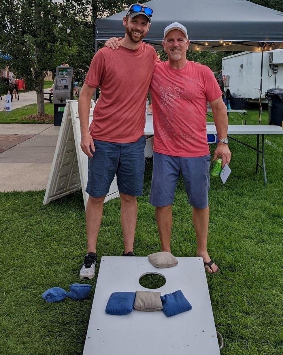 2 adults in red playing bags league